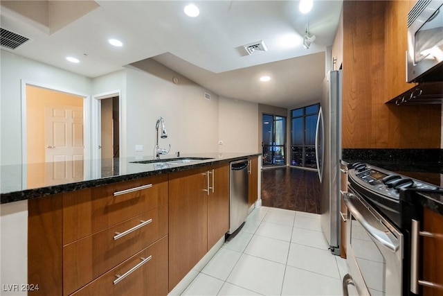 200 W Sahara Ave Unit 1510, Las Vegas, NV 89102 - kitchen with stainless steel appliances, brown cabinetry, dark stone counters, light tile patterned floors, and modern cabinets