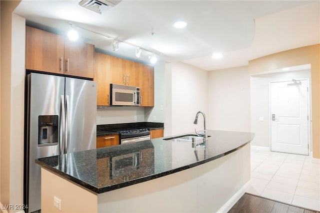200 W Sahara Ave Unit 1510, Las Vegas, NV 89102 - kitchen with stainless steel appliances, track lighting, a kitchen island with sink, dark stone counters, and brown cabinetry