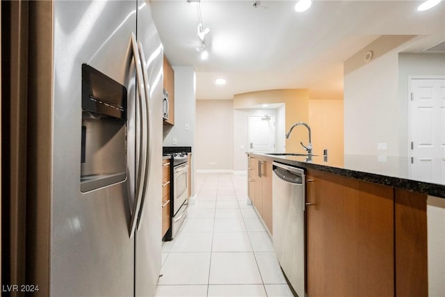 200 W Sahara Ave Unit 1510, Las Vegas, NV 89102 - kitchen featuring appliances with stainless steel finishes, light tile patterned flooring, recessed lighting, dark stone counters, and brown cabinetry