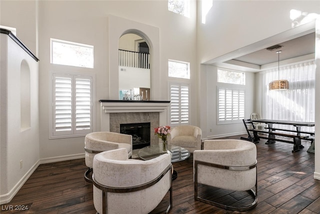 living room with dark hardwood / wood-style floors, plenty of natural light, a high end fireplace, and a towering ceiling