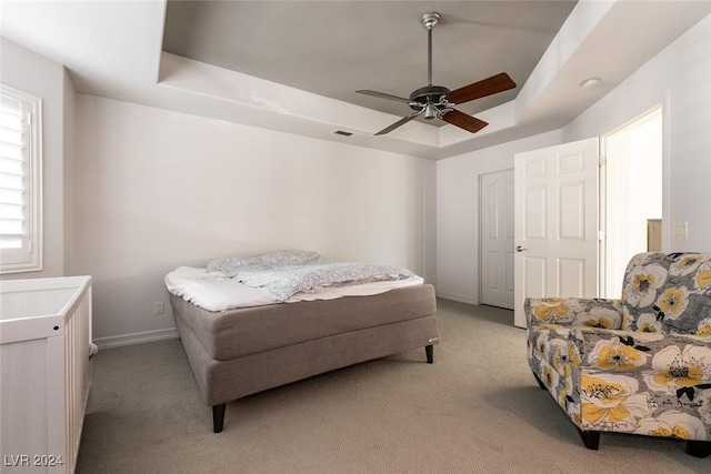 carpeted bedroom featuring a tray ceiling and ceiling fan