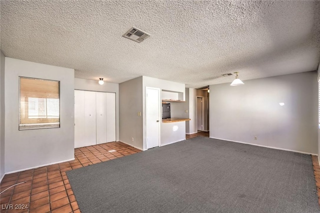 unfurnished living room featuring dark tile patterned floors and a textured ceiling