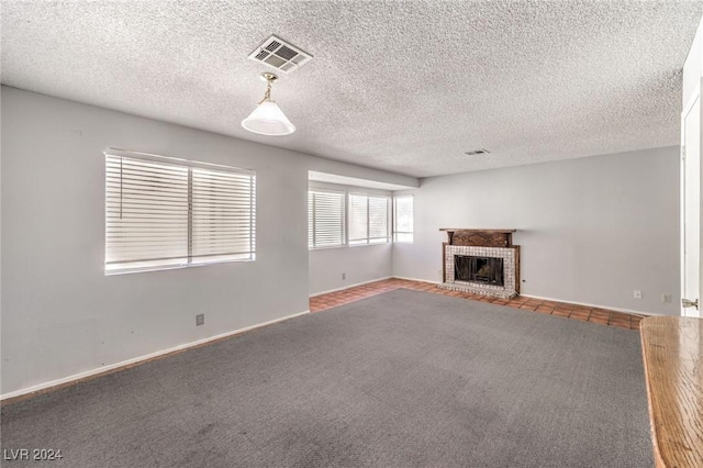 unfurnished living room featuring carpet flooring, a textured ceiling, and a brick fireplace