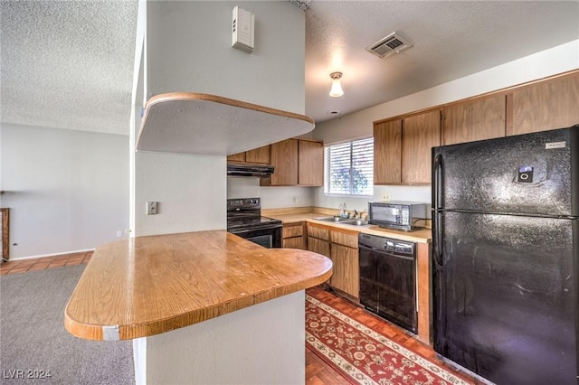 kitchen with black appliances, kitchen peninsula, sink, and exhaust hood