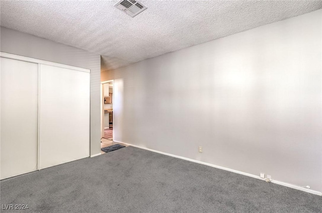 unfurnished bedroom with carpet, a textured ceiling, and a closet