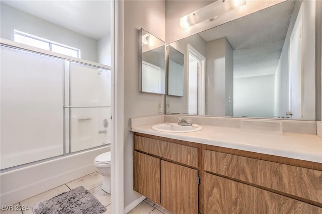 full bathroom featuring tile patterned flooring, vanity, toilet, and shower / bath combination with glass door