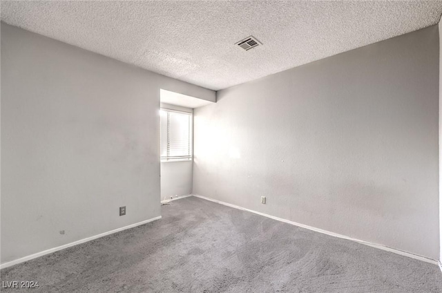 carpeted empty room featuring a textured ceiling