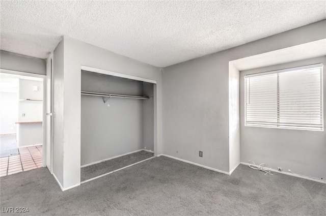 unfurnished bedroom featuring a closet, a textured ceiling, and dark colored carpet