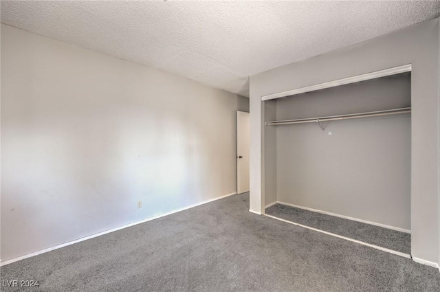 unfurnished bedroom with dark colored carpet, a textured ceiling, and a closet