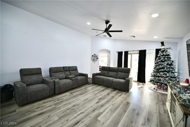 living room with ceiling fan, light hardwood / wood-style flooring, and vaulted ceiling