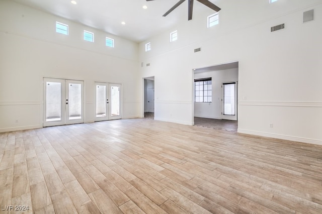 unfurnished living room featuring ceiling fan, french doors, a towering ceiling, and a healthy amount of sunlight