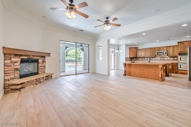 unfurnished living room with a fireplace, light hardwood / wood-style floors, ceiling fan with notable chandelier, and ornamental molding