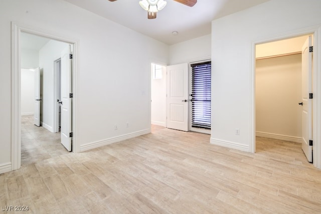 unfurnished bedroom featuring a walk in closet, ceiling fan, and light hardwood / wood-style floors