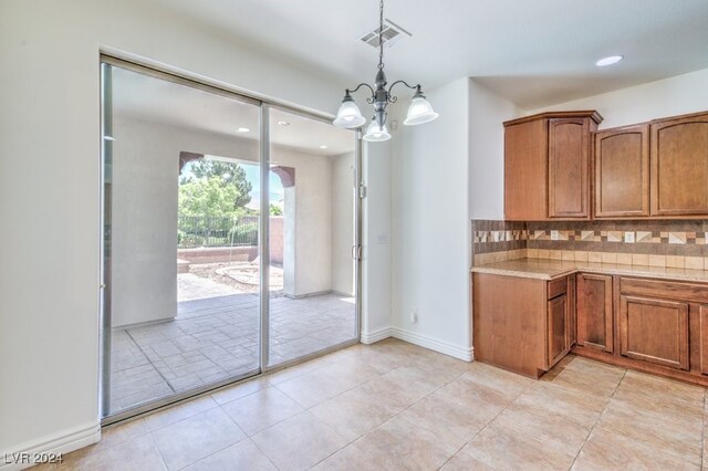 kitchen featuring decorative backsplash, light tile patterned floors, hanging light fixtures, and a chandelier