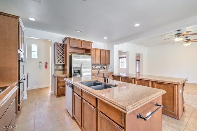 kitchen with a kitchen island with sink, crown molding, sink, ceiling fan, and appliances with stainless steel finishes