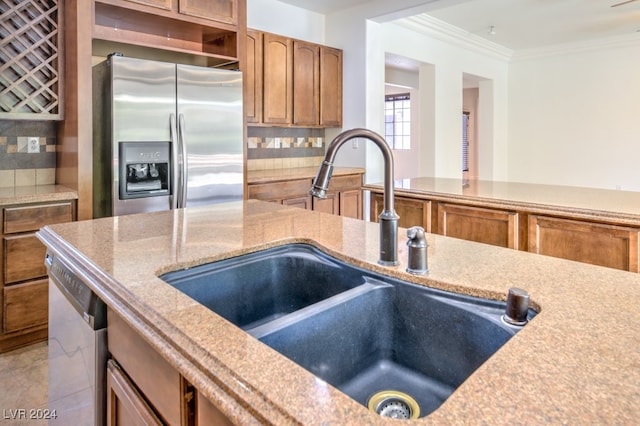 kitchen featuring tasteful backsplash, sink, ornamental molding, and appliances with stainless steel finishes