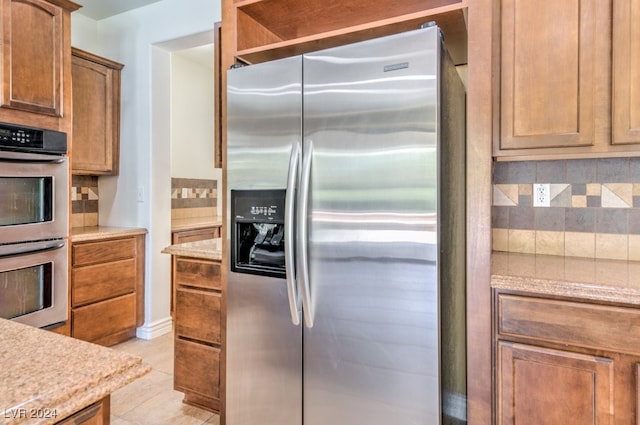 kitchen featuring stainless steel appliances, tasteful backsplash, and light tile patterned flooring