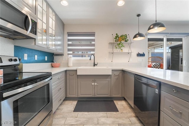 kitchen featuring appliances with stainless steel finishes, gray cabinets, a healthy amount of sunlight, and sink