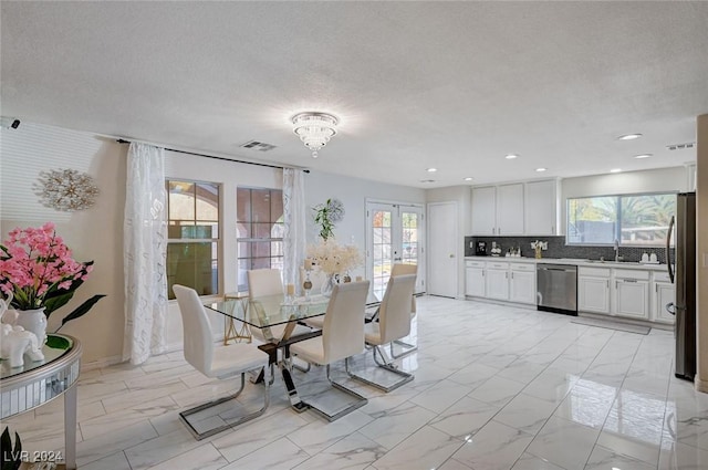 dining area with french doors, an inviting chandelier, a textured ceiling, and sink