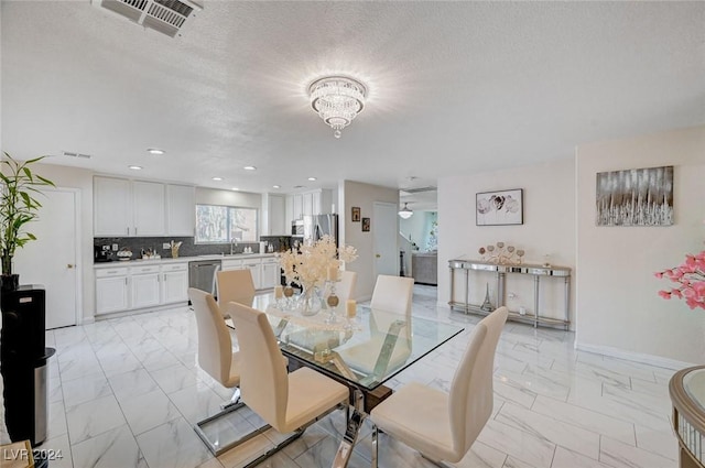 dining room with sink, a textured ceiling, and a chandelier