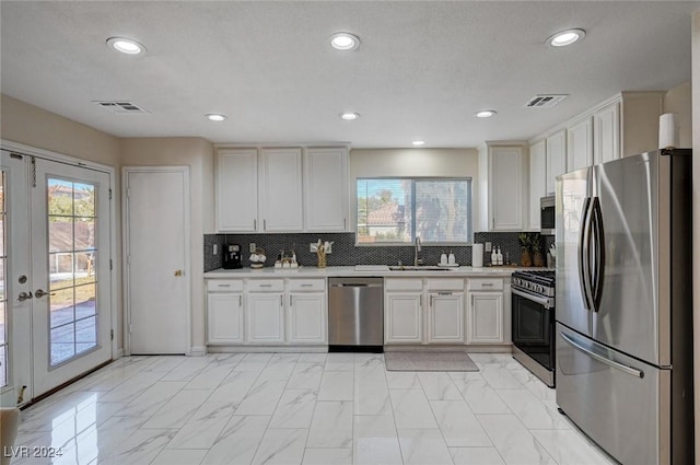 kitchen with french doors, white cabinets, sink, tasteful backsplash, and stainless steel appliances