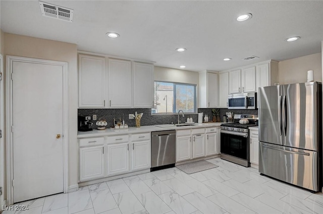 kitchen with backsplash, white cabinetry, sink, and appliances with stainless steel finishes