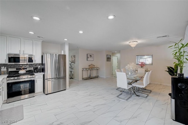 kitchen with stainless steel appliances, white cabinetry, and tasteful backsplash