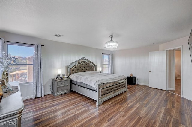 bedroom with a textured ceiling, dark hardwood / wood-style floors, and a notable chandelier