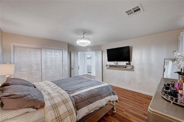 bedroom with a closet, wood-type flooring, and a notable chandelier