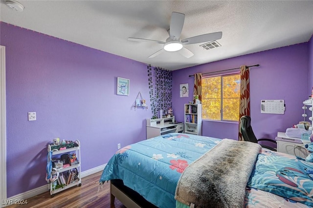 bedroom with a textured ceiling, ceiling fan, and dark wood-type flooring