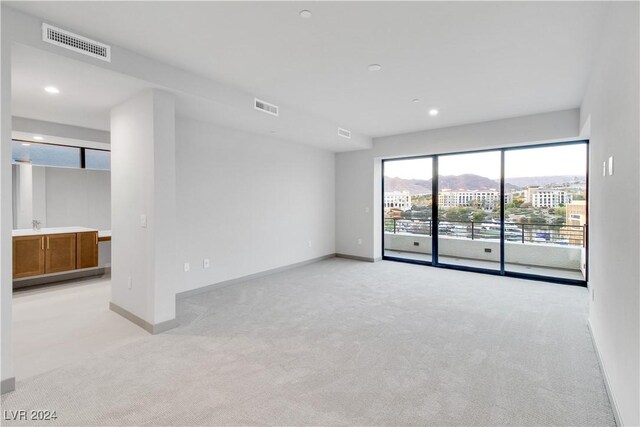 spare room with visible vents, light carpet, and baseboards