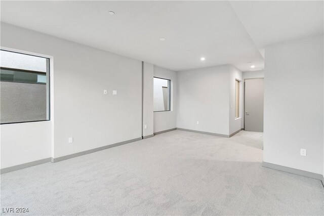 spare room with recessed lighting, plenty of natural light, baseboards, and light colored carpet