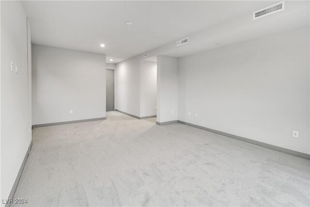 unfurnished room with light colored carpet, visible vents, and baseboards