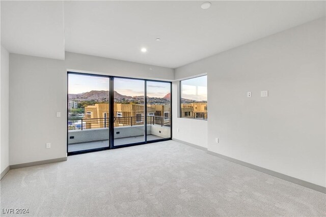 unfurnished room featuring light carpet, baseboards, a mountain view, and recessed lighting