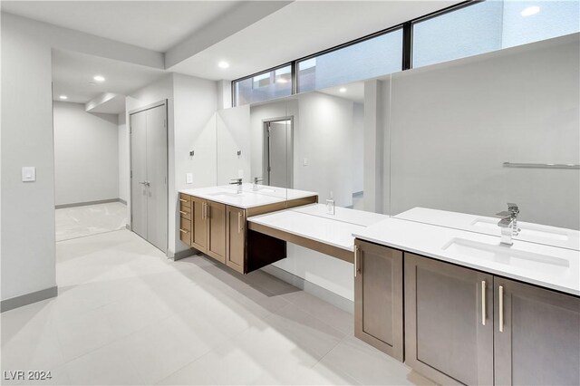 full bath with baseboards, two vanities, a sink, and recessed lighting