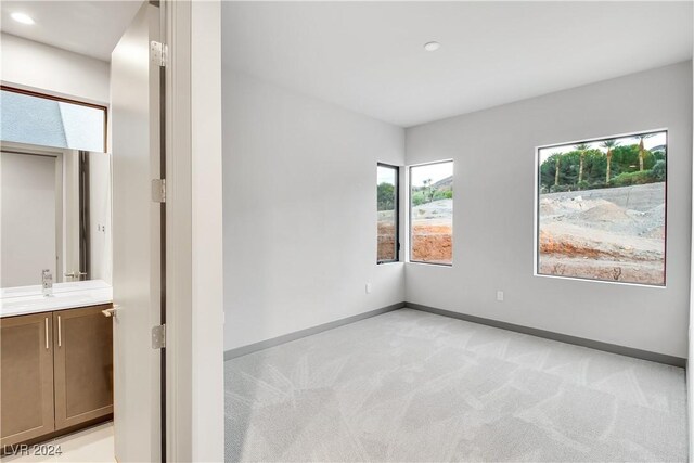 empty room featuring light carpet, recessed lighting, and baseboards