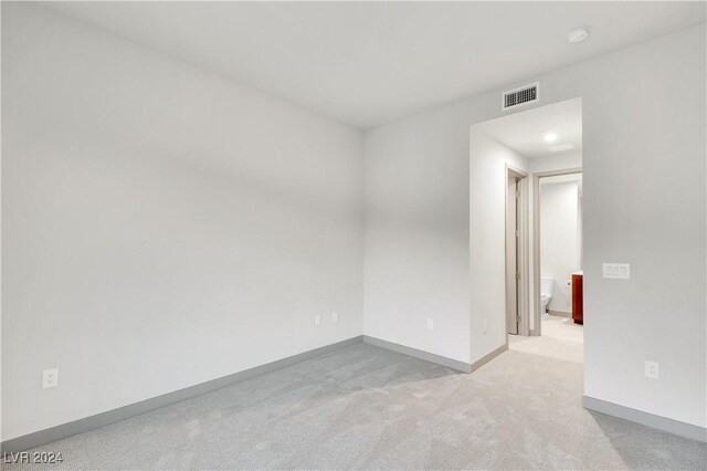 spare room with light colored carpet, visible vents, and baseboards