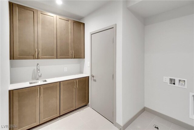 laundry room with cabinet space, light tile patterned floors, baseboards, hookup for a washing machine, and a sink