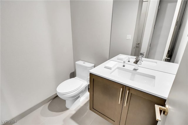 bathroom with toilet, vanity, and tile patterned flooring