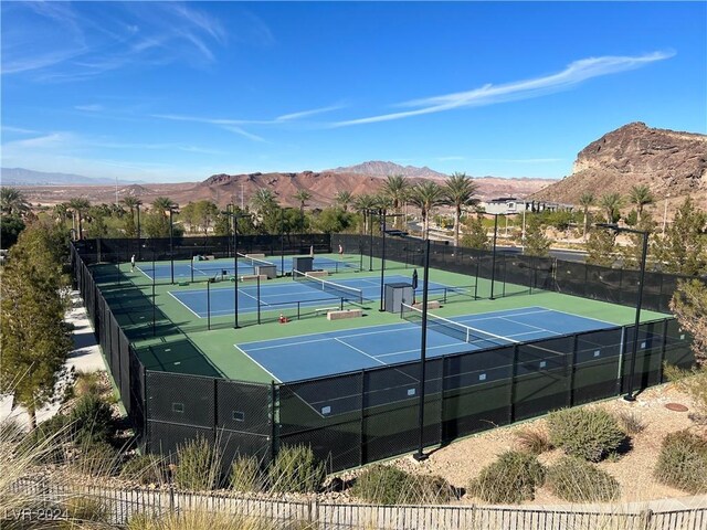 view of tennis court with a mountain view and fence