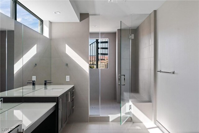 bathroom featuring a stall shower, tile patterned flooring, vanity, and tile walls