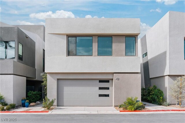 contemporary home with concrete driveway, an attached garage, and stucco siding