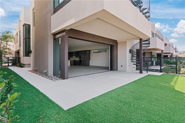 exterior space featuring driveway, a lawn, fence, and stucco siding