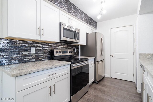 kitchen with light stone countertops, tasteful backsplash, stainless steel appliances, wood-type flooring, and white cabinets