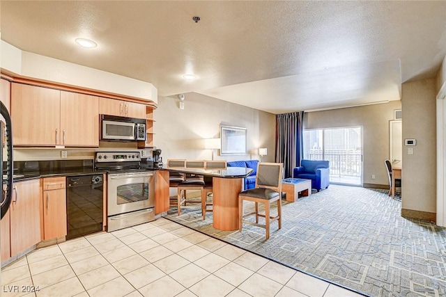 kitchen with a kitchen breakfast bar, light brown cabinetry, light tile patterned floors, and appliances with stainless steel finishes