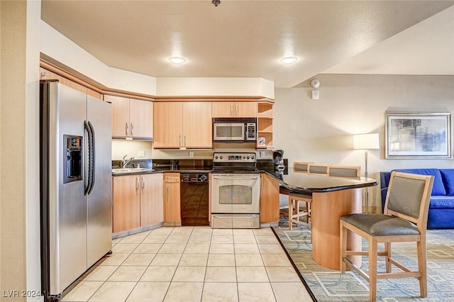 kitchen featuring light brown cabinets, sink, light tile patterned floors, appliances with stainless steel finishes, and kitchen peninsula