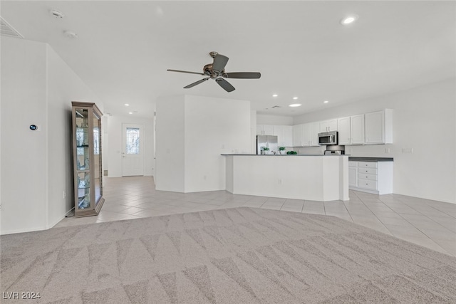 unfurnished living room with light colored carpet and ceiling fan