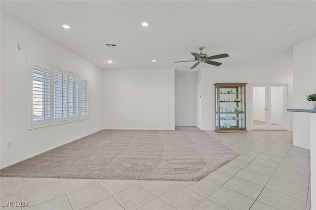 empty room featuring ceiling fan, french doors, and light colored carpet