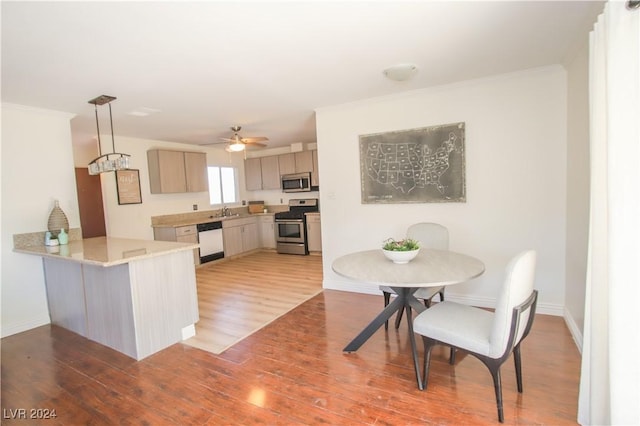 kitchen with kitchen peninsula, stainless steel appliances, light brown cabinets, pendant lighting, and light hardwood / wood-style flooring