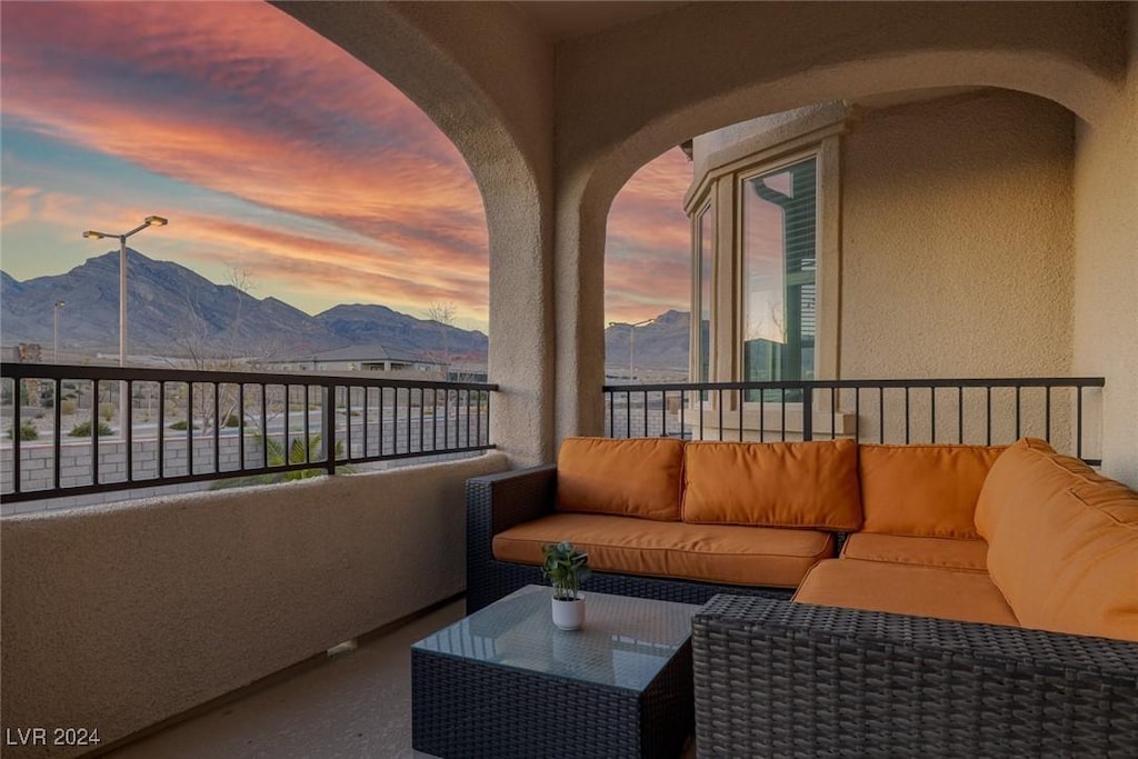 balcony at dusk featuring a mountain view and an outdoor living space